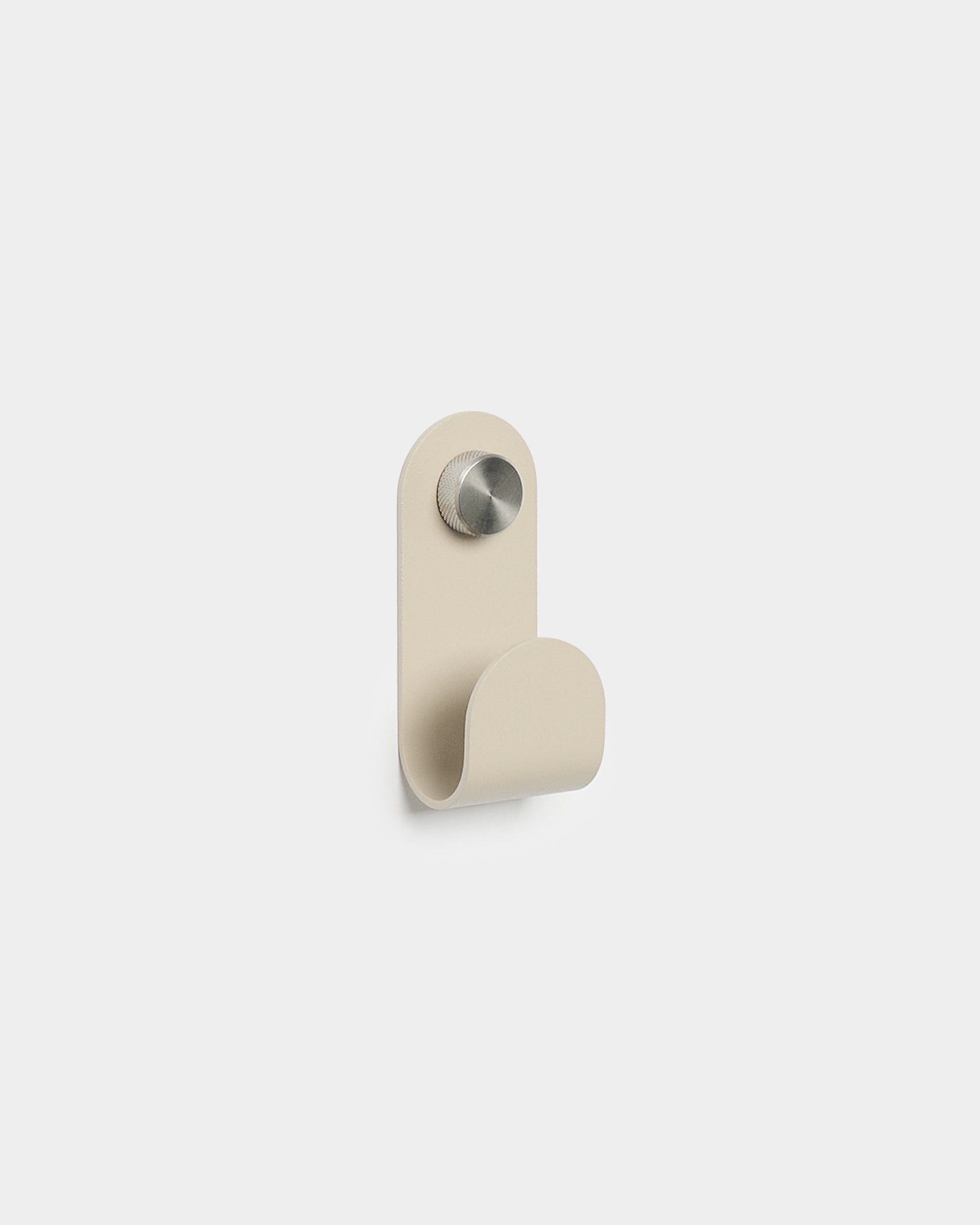 WoodUpp Norr Single Hanger en beige, avec une forme courbée minimaliste et une finition en métal brossé, conçu comme accessoire pour des patères murales compactes Akupanel.